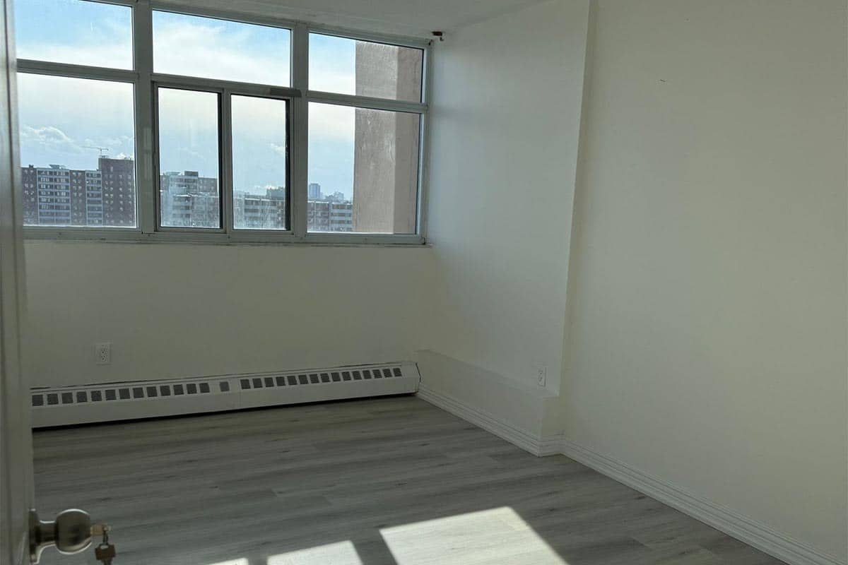 Bedroom in a Scarborough condo with a band of windows, where replacement vs enlarged window opening rules differ because the building is not a single-unit house